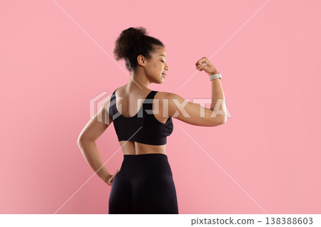 Athletic Black woman in black sports bra flexing single bicep from behind Athletic Black woman in black sports bra flexing single bicep from behind 138388603