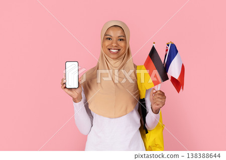 Black Muslim woman student in hijab holding blank smartphone and international flags Black Muslim woman student in hijab holding blank smartphone and international flags 138388644