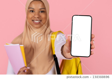 Young black Muslim woman student in hijab extending blank smartphone toward camera 138388696