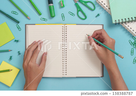 Writing in a notebook with green stationery Writing in a notebook with green stationery 138388787