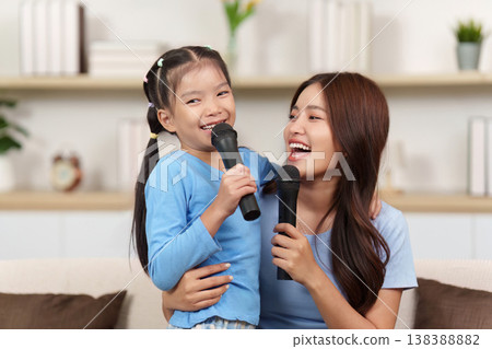 Mother and daughter singing together at home 138388882