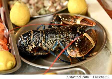 Fresh whole lobster on plate with lemon in seafood restaurant Fresh whole lobster on plate with lemon in seafood restaurant 138390089