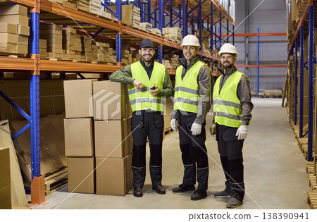 Portrait of warehouse team with boxes on racks, ready for packing and dispatch Portrait of warehouse team with boxes on racks, ready for packing and dispatch 138390941