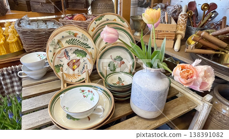 Beautiful hand painted ceramic plates and fresh pink tulips in a rustic gift shop display interior 138391082