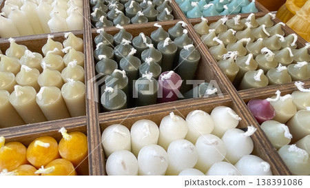 Close up of various colorful handmade wax candles neatly organized in a wooden divider box display Close up of various colorful handmade wax candles neatly organized in a wooden divider box display 138391086