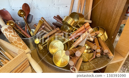 Elegant gold and wooden kitchen utensils with carved rolling pin in a rustic boutique shop display 138391090