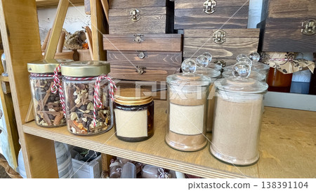 Rustic display of glass spice jars and wooden storage boxes on a shelf in a boutique artisan shop Rustic display of glass spice jars and wooden storage boxes on a shelf in a boutique artisan shop 138391104