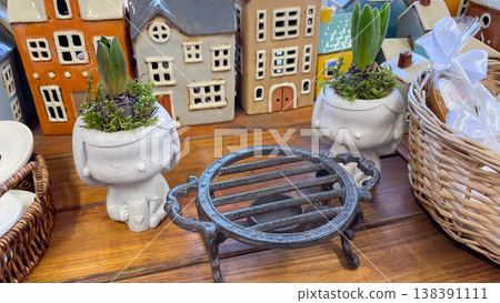 Whimsical human-shaped ceramic planters with spring hyacinths and decorative miniature houses on a wooden shelf Whimsical human-shaped ceramic planters with spring hyacinths and decorative miniature houses on a wooden shelf 138391111
