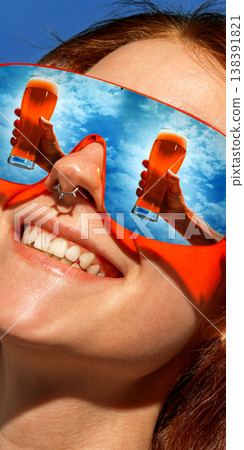Woman in red sunglasses with cold beer glasses reflected in lenses smiling outdoors. 138391821