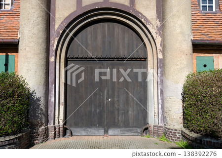 Old wooden arched door on historic building facade with textured wall and traditional architecture detail exterior design concept Old wooden arched door on historic building facade with textured wall and traditional architecture detail exterior design concept 138392276