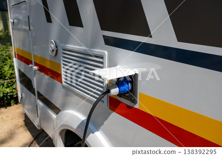 Camper van electrical hookup with power cable connected to RV outlet for mobile travel energy supply concept Camper van electrical hookup with power cable connected to RV outlet for mobile travel energy supply concept 138392295