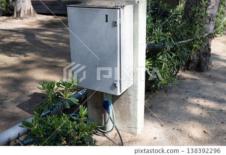 Outdoor electrical control box with cable connection on concrete post in urban garden environment with infrastructure utility concept Outdoor electrical control box with cable connection on concrete post in urban garden environment with infrastructure utility concept 138392296