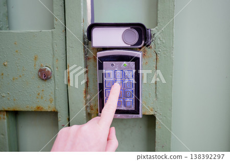 Person entering security code on electronic keypad access control system at metal gate with secure entry concept Person entering security code on electronic keypad access control system at metal gate with secure entry concept 138392297