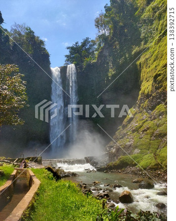 Majestic waterfall surrounded by lush greenery and mist, creating a serene natural paradise Majestic waterfall surrounded by lush greenery and mist, creating a serene natural paradise 138392715