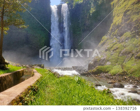 Majestic waterfall surrounded by lush greenery and mist, creating a serene natural paradise Majestic waterfall surrounded by lush greenery and mist, creating a serene natural paradise 138392716