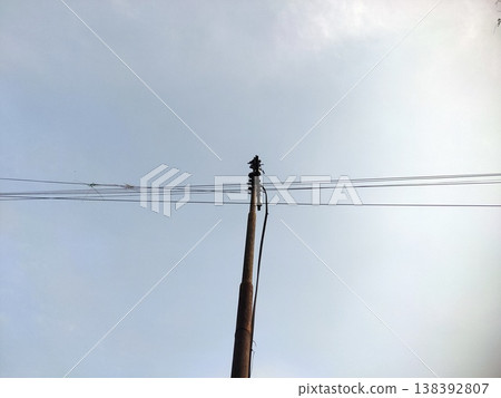 Wooden utility pole and wires clean sky backdrop frames urban infrastructure in quiet daylight Wooden utility pole and wires clean sky backdrop frames urban infrastructure in quiet daylight 138392807