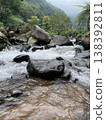Crystal-clear river flowing over smooth rocks, framed by lush forest and misty mountain views. 138392811