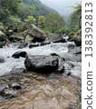 Crystal-clear river flowing over smooth rocks, framed by lush forest and misty mountain views. 138392813
