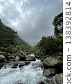 Crystal-clear river flowing over smooth rocks, framed by lush forest and misty mountain views. 138392814