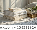 Soft folded towels and bed linen stack in cozy bedroom with natural sunlight 138392820
