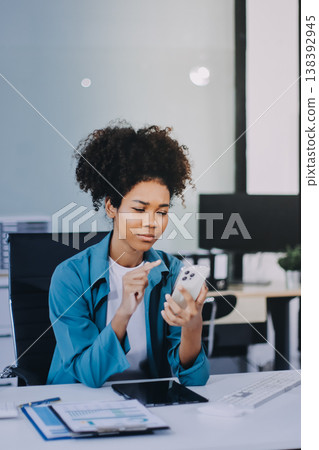 Young African American black woman working on laptop and mobile phone Young African American black woman working on laptop and mobile phone 138392945