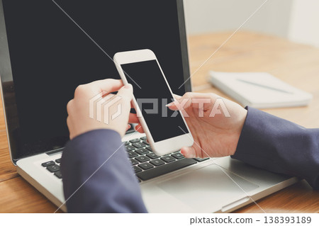 Woman using computer and mobile phone, selective focus, close-up, copy space on the screen 138393189