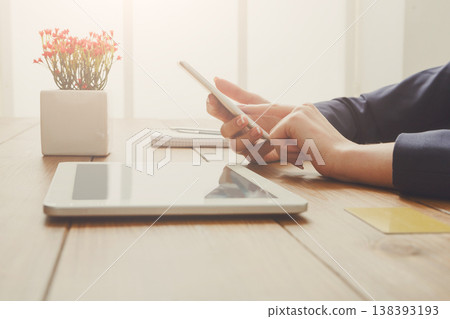 Woman using phone for online payment while sitting at wooden table, close-up, side view. Woman using phone for online payment while sitting at wooden table, close-up, side view. 138393193