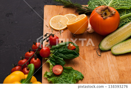 Cooking healthy vegetarian food background. Fresh organic vegetables on black. Natural food and wooden cutting board with copy space on black Cooking healthy vegetarian food background. Fresh organic vegetables on black. Natural food and wooden cutting board with copy space on black 138393276