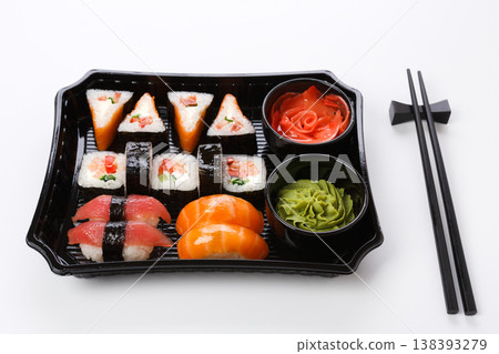 Japanese food restaurant delivery, take away box, sushi maki and roll set. Chopsticks, ginger, soy sauce, wasabi. Meals isolated at white background Japanese food restaurant delivery, take away box, sushi maki and roll set. Chopsticks, ginger, soy sauce, wasabi. Meals isolated at white background 138393279