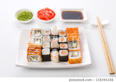 Traditional japanese food delivery. Sushi set on white plate, soy sauce, ginger, wasabi and chopsticks aside. Colorful rolls and gunkan assortment at white background, pov 138393288