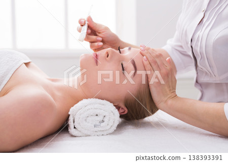 Apply face mask, spa beauty treatment and skincare. Woman getting facial nourishing mask by beautician at spa salon, close-up 138393391