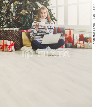 Christmas online shopping. Woman has coffee, buy presents on laptop, prepare to xmas, among gift boxes and packages. Winter sales Christmas online shopping. Woman has coffee, buy presents on laptop, prepare to xmas, among gift boxes and packages. Winter sales 138393445