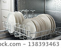 Clean dishes inside dishwasher with water drops and modern kitchen appliance 138393463