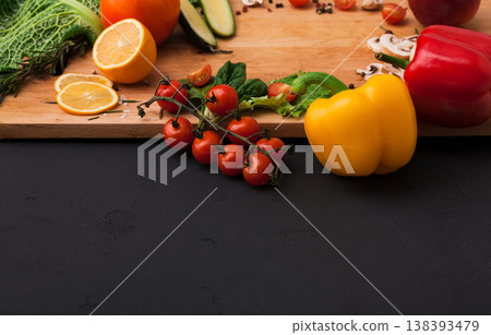 Cooking healthy vegetarian food background. Fresh organic vegetables on black. Natural food and wooden cutting board with copy space on black Cooking healthy vegetarian food background. Fresh organic vegetables on black. Natural food and wooden cutting board with copy space on black 138393479