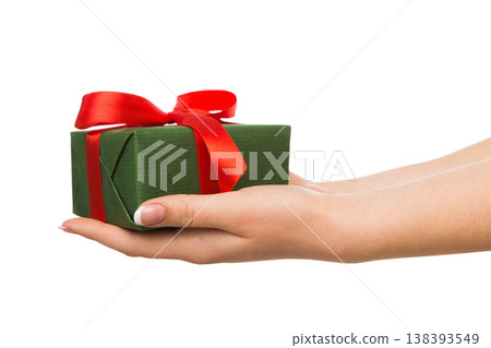 Woman's hands give present box isolated on white. Gift in paper with red ribbon. 138393549