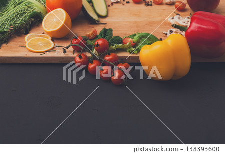 Cooking healthy vegetarian food background. Fresh organic vegetables on black. Natural food and wooden cutting board with copy space on black Cooking healthy vegetarian food background. Fresh organic vegetables on black. Natural food and wooden cutting board with copy space on black 138393600