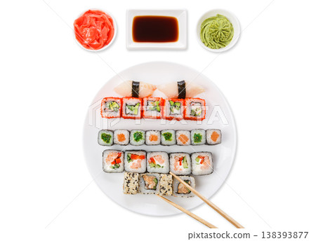 Japanese food restaurant. Sushi set served on white platter with soy sauce, ginger and wasabi and chopsticks picking one piece. Top view at white background with copy space Japanese food restaurant. Sushi set served on white platter with soy sauce, ginger and wasabi and chopsticks picking one piece. Top view at white background with copy space 138393877