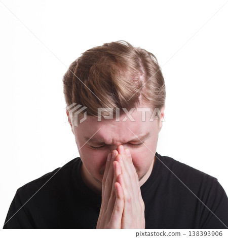 Hopeful man praying, holding hands clasped near face on white isolated studio background Hopeful man praying, holding hands clasped near face on white isolated studio background 138393906