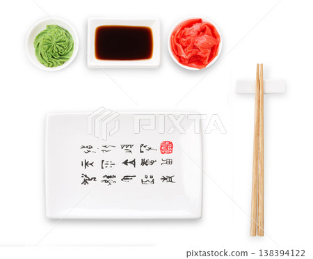 Set of sushi tablewear. Top view on empty rectangular sushi plate with hieroglyphs, saucer, ginger, wasabi and chopsticks at white background. Flat lay, copy space 138394122