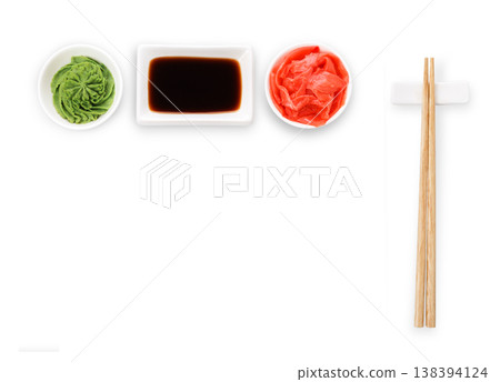 Set of sushi tablewear. Top view on saucer with soy sauce, small white bowls for ginger and wasabi and chopsticks at white background. Flat lay, copy space 138394124