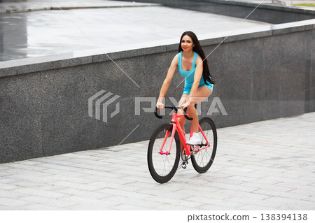 Sexy girl with bicycle. Young slim sexy sporty woman in blue shorts and white snickers long-haired, sensual riding at pink fix bicycle in urban city environment. Soft toned. Sexy girl with bicycle. Young slim sexy sporty woman in blue shorts and white snickers long-haired, sensual riding at pink fix bicycle in urban city environment. Soft toned. 138394138