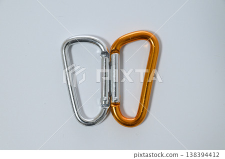Two carabiners of different colors, side by side and facing each other. 138394412