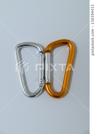 Silver and orange carabiners lined up vertically 138394413