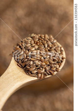 flax seeds in a wooden spoon, a simple spoon filled with fresh flax seeds 138394563