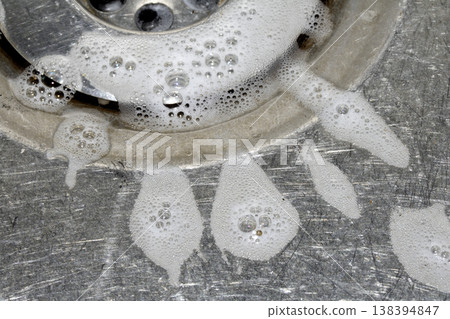 Close up of washing up liquid bubbles flowing down the kitchen sink 138394847