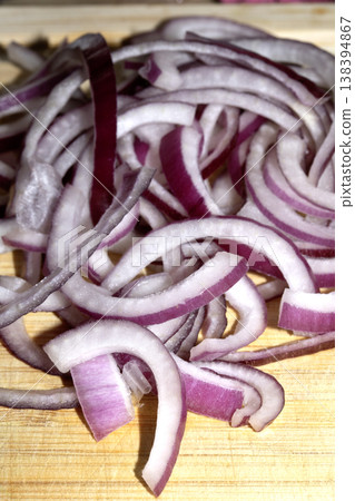 Close up of finely chopped sliced red onion salad vegetables on wooden chopping board 138394867