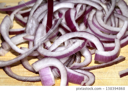 Close up of finely chopped sliced red onion salad vegetables on wooden chopping board Close up of finely chopped sliced red onion salad vegetables on wooden chopping board 138394868