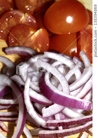 Close up of finely chopped sliced red onion salad vegetables on wooden chopping board Close up of finely chopped sliced red onion salad vegetables on wooden chopping board 138394869