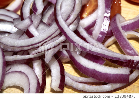 Close up of finely chopped sliced red onion salad vegetables on wooden chopping board Close up of finely chopped sliced red onion salad vegetables on wooden chopping board 138394873