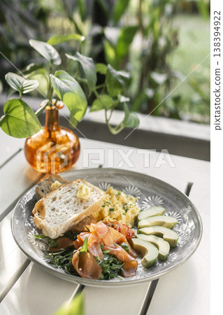 smoked salmon with avocado salad and scrambled eggs healthy breakfast plate in outdoor cafe 138394922